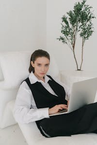 Confident woman in business attire using a laptop indoors. Modern, professional atmosphere.