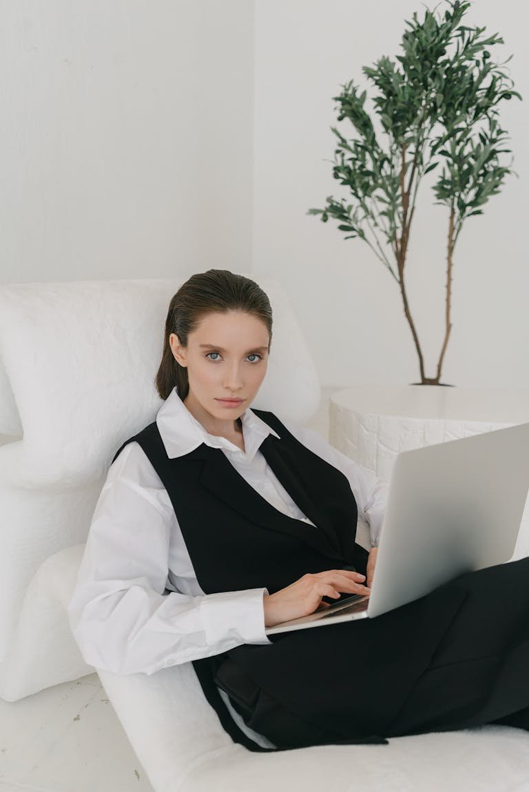 Confident woman in business attire using a laptop indoors. Modern, professional atmosphere.