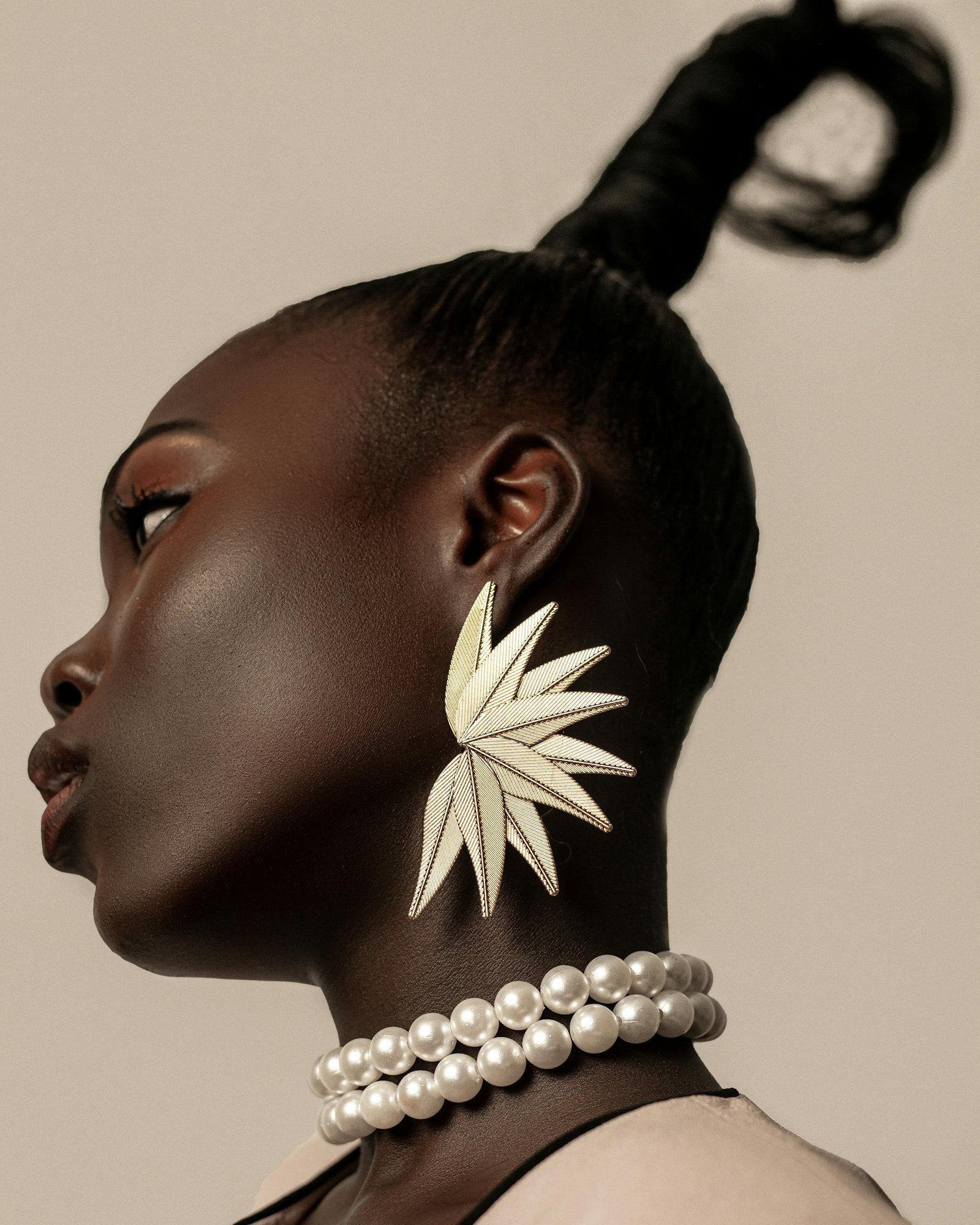 Elegant profile of a woman wearing large leaf-shaped earrings, showcasing fashion and style.