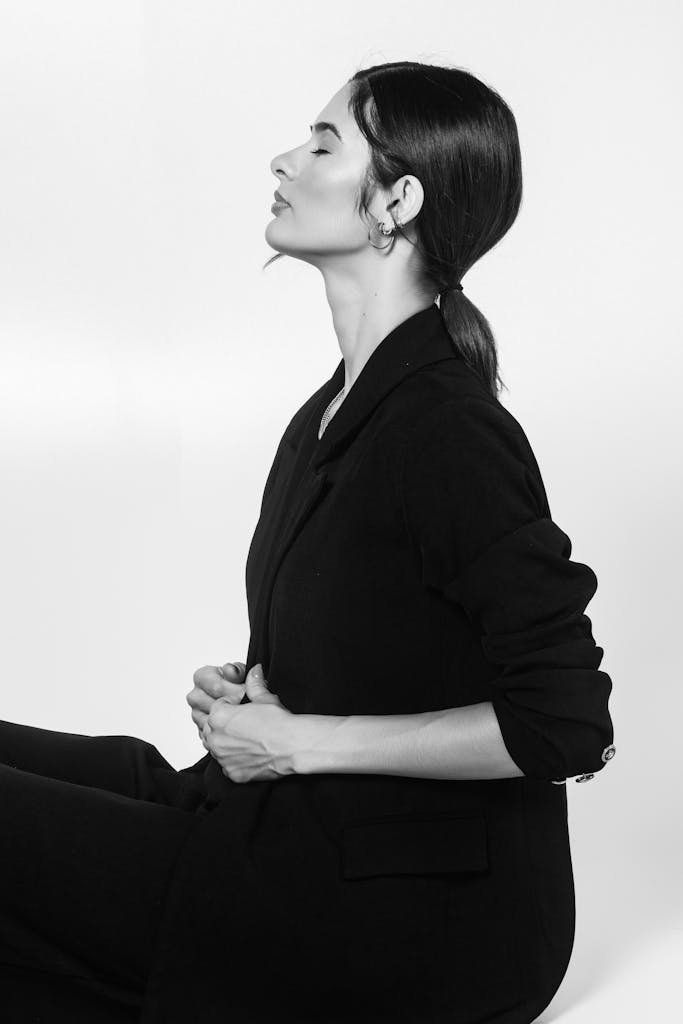 Sophisticated black and white studio portrait of a woman in a suit with eyes closed.