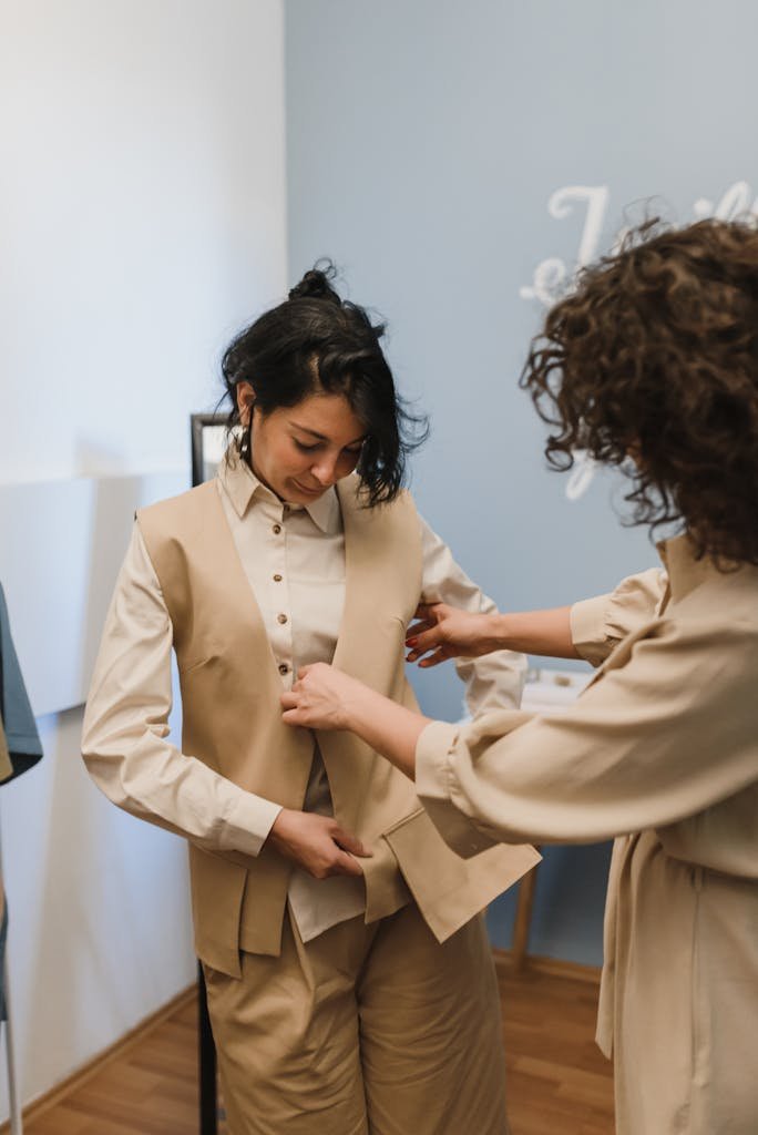 A boutique tailor adjusting a vest for a young customer inside a shop.
