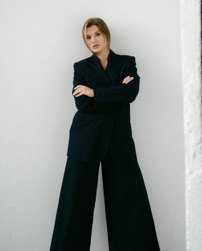 Businesswoman in elegant attire posing confidently against a minimalist backdrop.